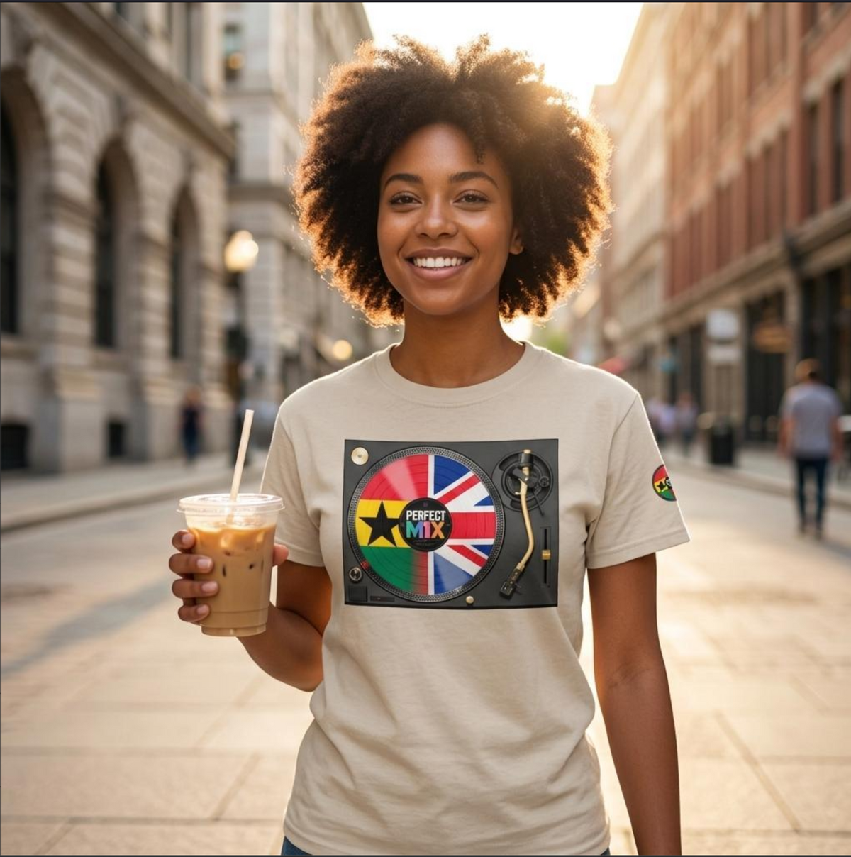 AI generated image of a smiling woman with an afro stands on a city street holding an iced coffee, wearing a beige graphic t-shirt. The t-shirt features a DJ turntable and vinyl with the text 'PERFECT MIX' and the Ghanaian and British flags.