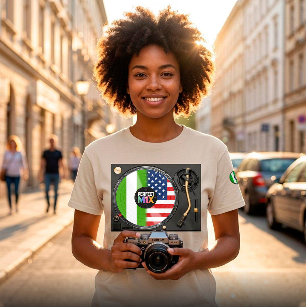 AI generated image of a smiling woman with an afro hairstyle stands on a sunlit city street holding a camera. She is wearing a light beige graphic T-shirt featuring a vinyl record design with the Nigerian and American flags, with the words 'PERFECT MIX'.